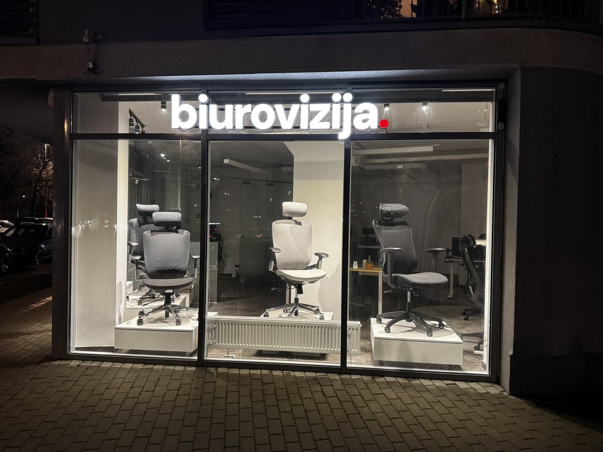 The BiuroVizija showroom at night, office chairs lit in the window