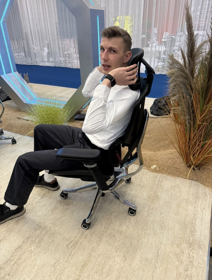 Lukas trying the headrest and back support of a chair at a furniture fair
